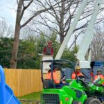 Arborists from Godspeed Tree Service using a bucket truck to prune brnaches of trees on a property in Winston-Salem, NC.